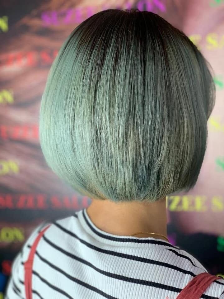 Rambut bob pendek warna hijau mint, dilihat dari belakang di hadapan latar bercetak Suzee Salon