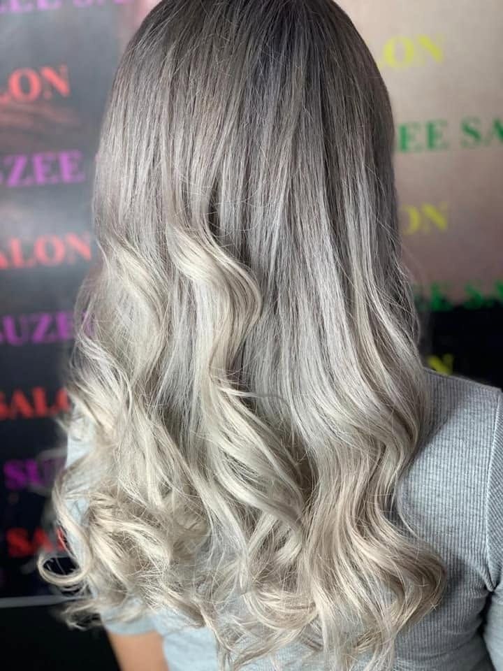 Rambut panjang beralun, pangkal gelap ke hujung silver, dilihat dari belakang di hadapan latar bercetak Suzee Salon