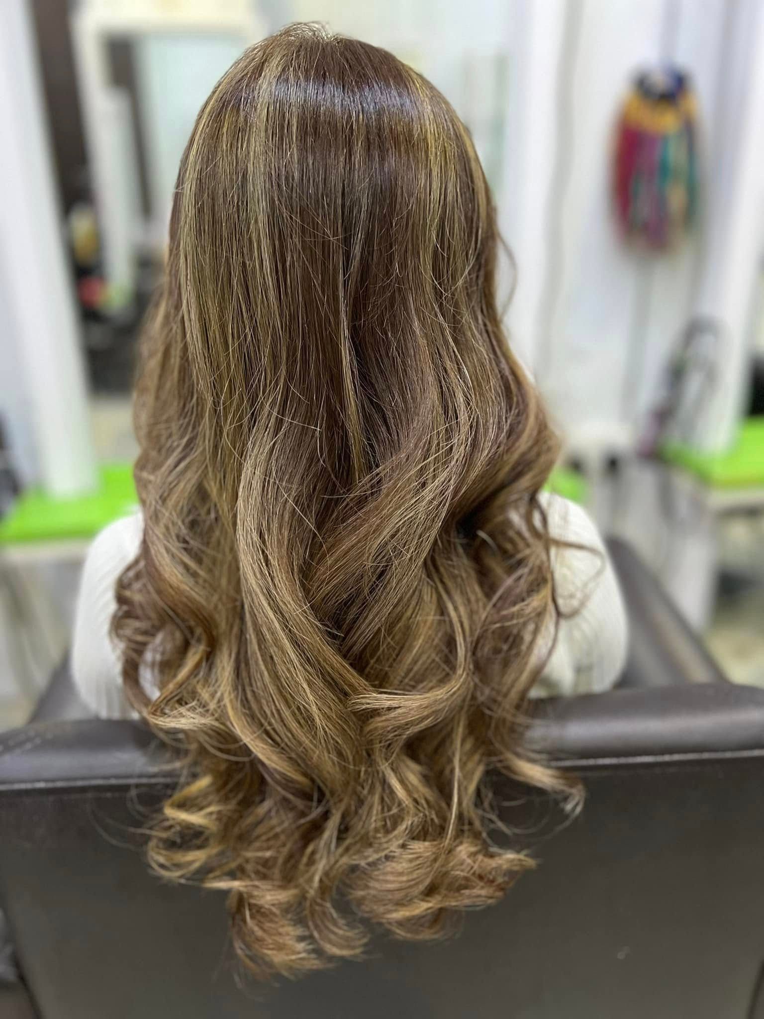 Rambut panjang beralun dengan balayage perang lembut, dilihat dari belakang di Suzee Salon