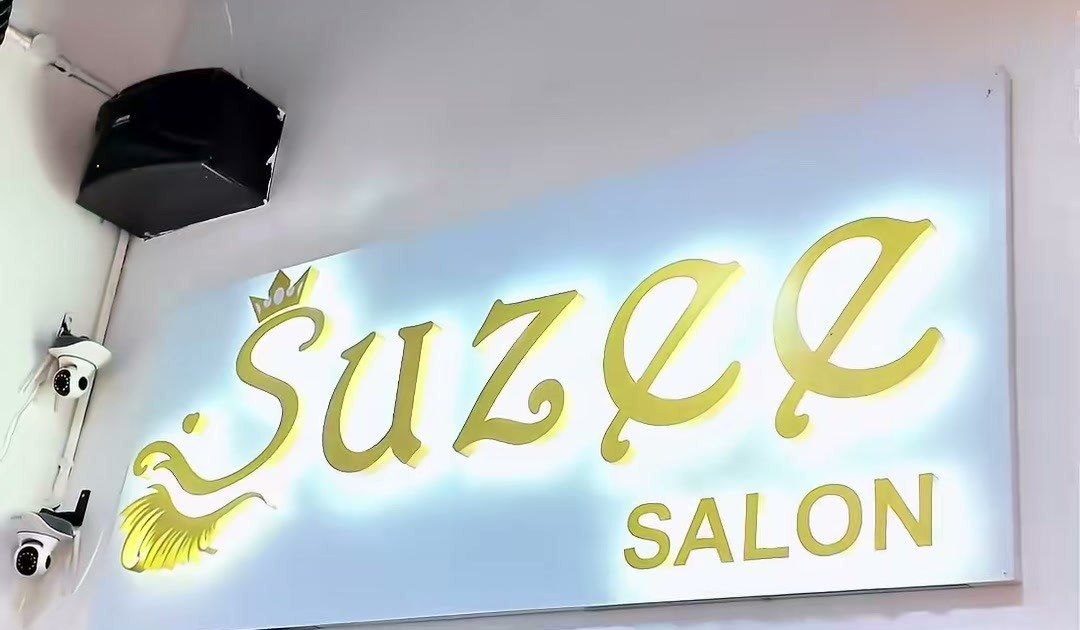 Papan tanda Suzee Salon bercahaya warna emas dengan mahkota di atas huruf S